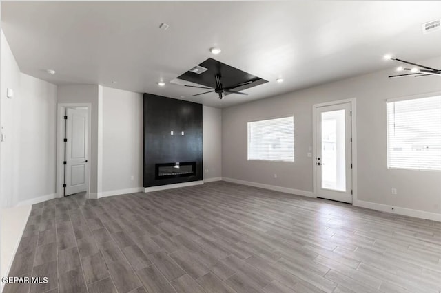 unfurnished living room with ceiling fan, plenty of natural light, light hardwood / wood-style flooring, and a large fireplace