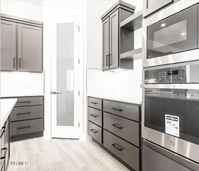 kitchen featuring light wood-type flooring, stainless steel appliances, and gray cabinets