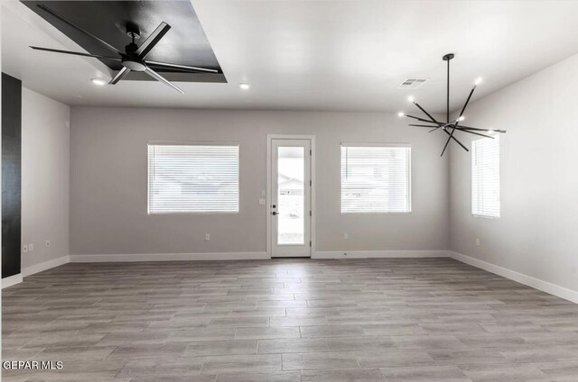 empty room featuring ceiling fan with notable chandelier