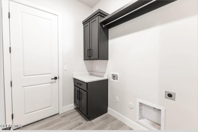 clothes washing area with light hardwood / wood-style flooring, hookup for a gas dryer, cabinets, electric dryer hookup, and washer hookup