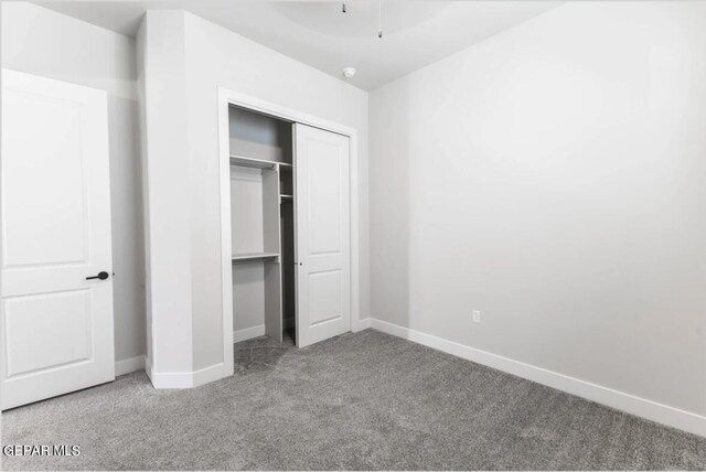 unfurnished bedroom featuring light carpet and a closet