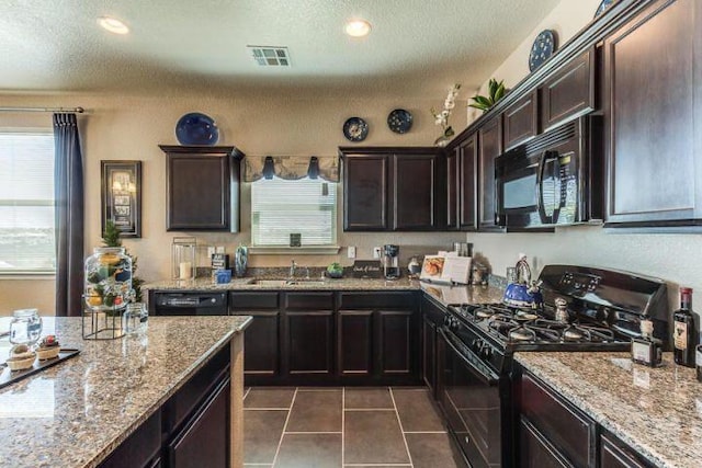 kitchen with plenty of natural light, dark tile patterned floors, dark brown cabinets, and black appliances