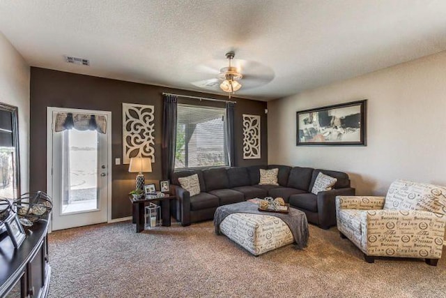 carpeted living room with a textured ceiling and ceiling fan