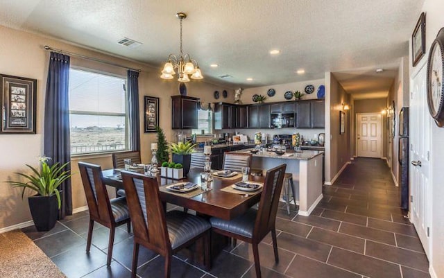 tiled dining room with a notable chandelier and a textured ceiling