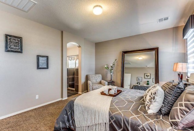 carpeted bedroom with ensuite bathroom and a textured ceiling