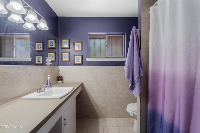 bathroom featuring tile patterned flooring, vanity, toilet, and tile walls