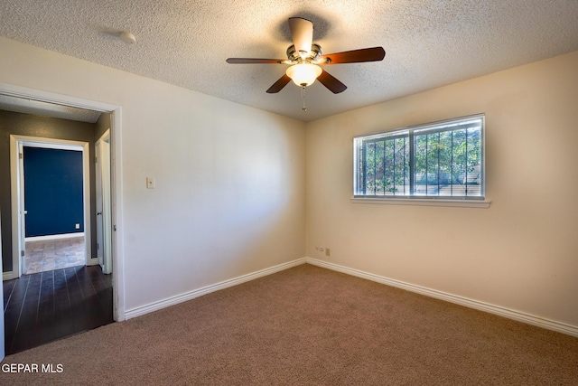 empty room featuring ceiling fan, dark carpet, and a textured ceiling