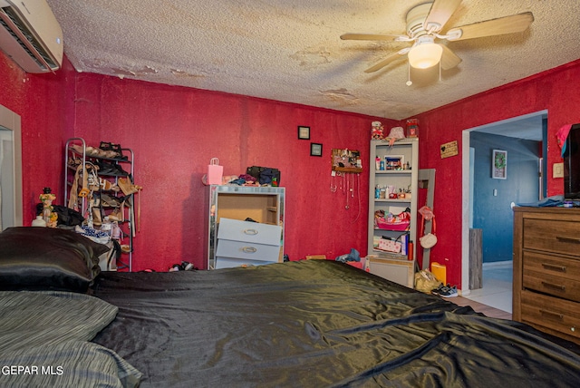 tiled bedroom featuring a wall mounted air conditioner, ceiling fan, and a textured ceiling