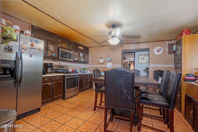 kitchen with a textured ceiling, a ceiling fan, stainless steel appliances, and dark brown cabinets