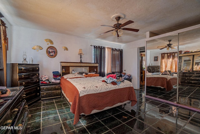 bedroom featuring a ceiling fan, dark tile patterned flooring, and a textured ceiling