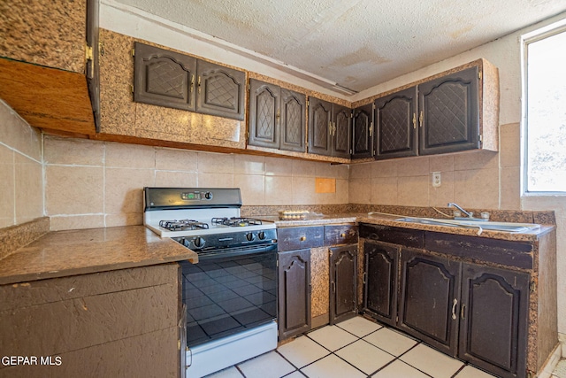 kitchen with a textured ceiling, white gas range oven, a sink, and dark brown cabinetry