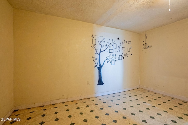 spare room featuring baseboards, a textured ceiling, and light floors