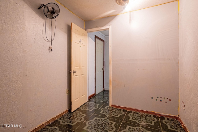 empty room featuring a textured wall and baseboards