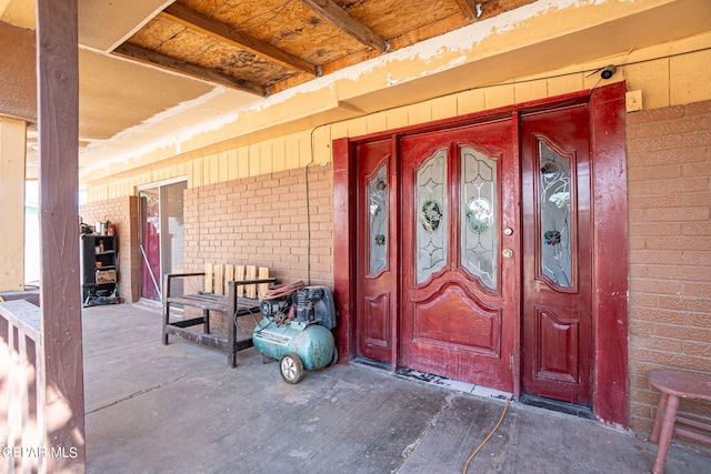 property entrance with covered porch and brick siding