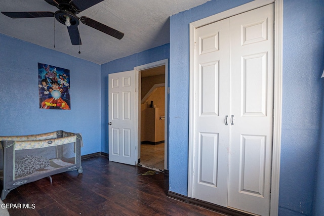 bedroom featuring a closet, dark wood-type flooring, ceiling fan, a textured ceiling, and baseboards