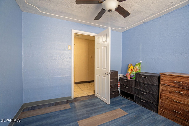 bedroom featuring a textured ceiling, baseboards, wood finished floors, and a textured wall