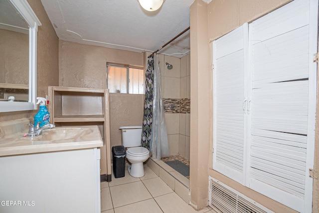 bathroom with a stall shower, toilet, tile patterned flooring, a textured ceiling, and vanity