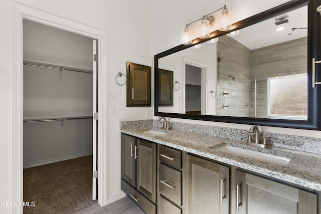 bathroom with a tile shower and double sink vanity