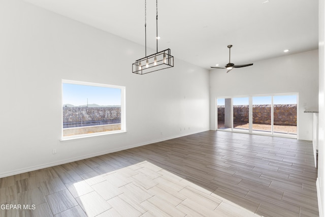 interior space with a towering ceiling, ceiling fan with notable chandelier, and a wealth of natural light