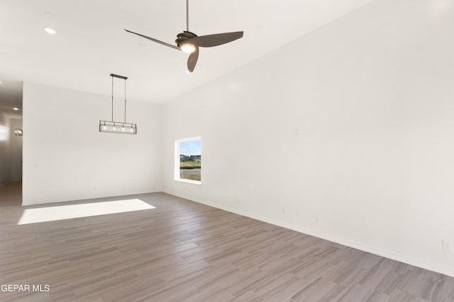 empty room with ceiling fan, high vaulted ceiling, and light hardwood / wood-style flooring