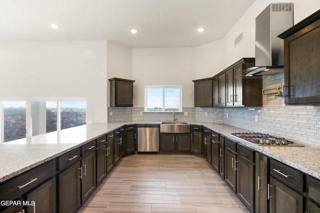 kitchen featuring appliances with stainless steel finishes, sink, tasteful backsplash, light stone counters, and wall chimney range hood