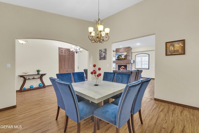 dining area with light hardwood / wood-style floors, a brick fireplace, brick wall, and a chandelier