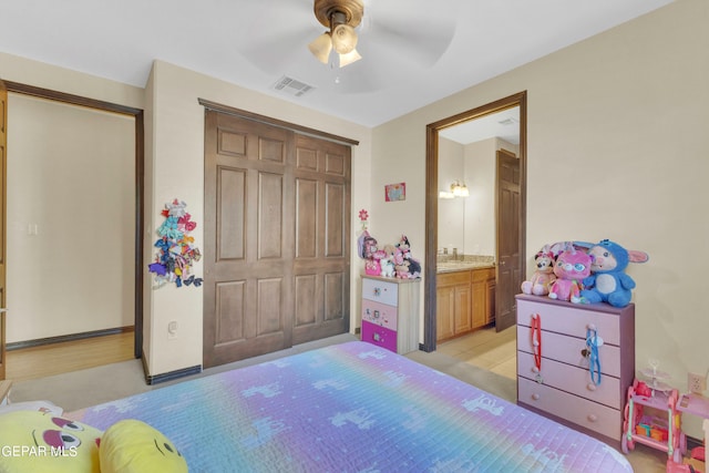 bedroom featuring light hardwood / wood-style floors, a closet, ensuite bath, and ceiling fan