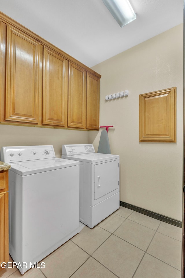 washroom with light tile patterned flooring, washer and clothes dryer, and cabinets