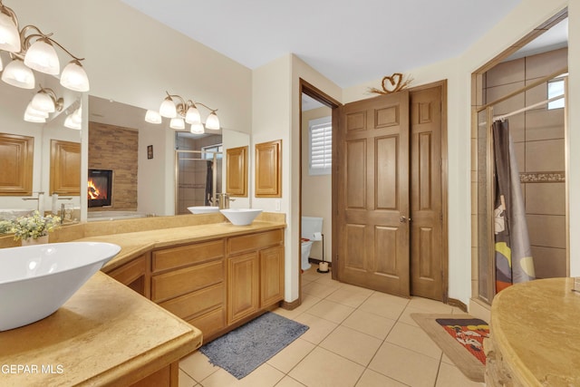 bathroom with a large fireplace, vanity, tile patterned floors, and plenty of natural light