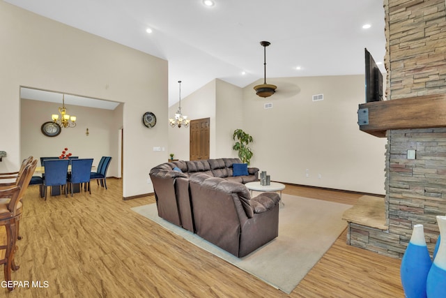 living room featuring an inviting chandelier, high vaulted ceiling, and light hardwood / wood-style flooring