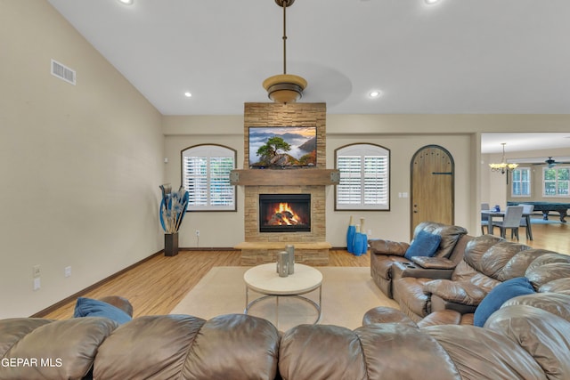 living room featuring a stone fireplace, light hardwood / wood-style flooring, and plenty of natural light