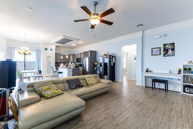 living room featuring ceiling fan with notable chandelier and hardwood / wood-style floors