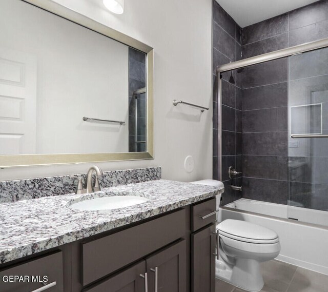 full bathroom featuring tile patterned floors, vanity, toilet, and shower / bath combination with glass door