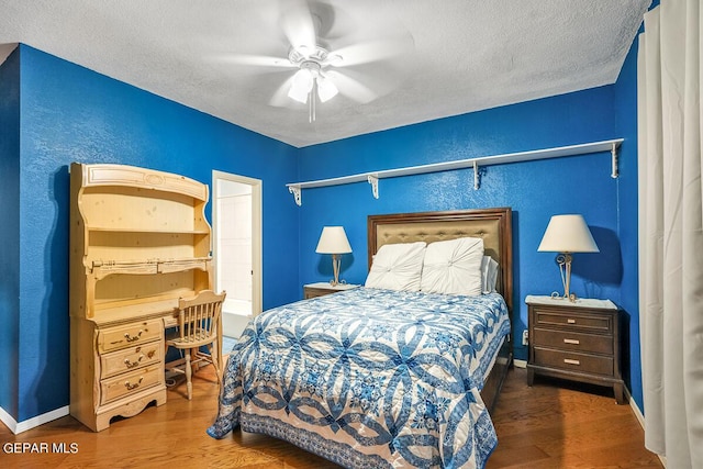 bedroom with ceiling fan, dark hardwood / wood-style flooring, and a textured ceiling