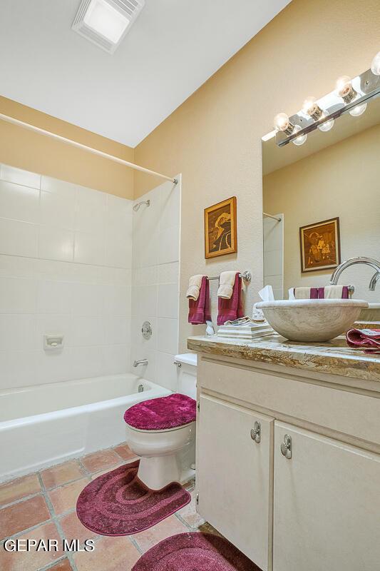 full bathroom featuring vanity, tiled shower / bath, tile patterned floors, and toilet