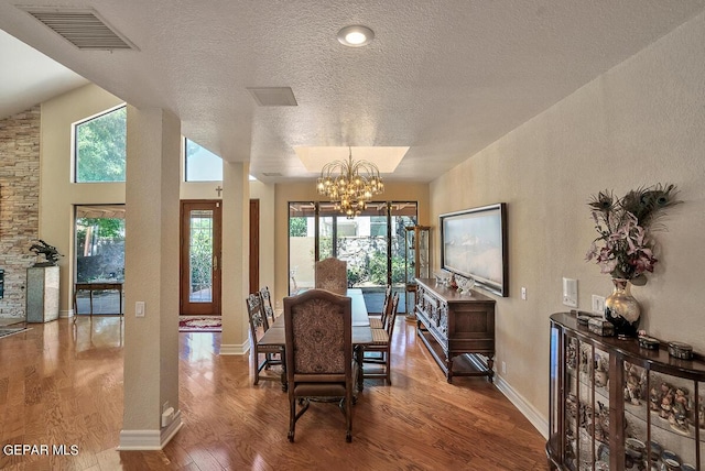 dining room with hardwood / wood-style flooring, a textured ceiling, and an inviting chandelier