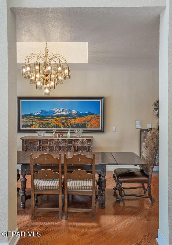 dining room featuring wood-type flooring, a textured ceiling, and an inviting chandelier