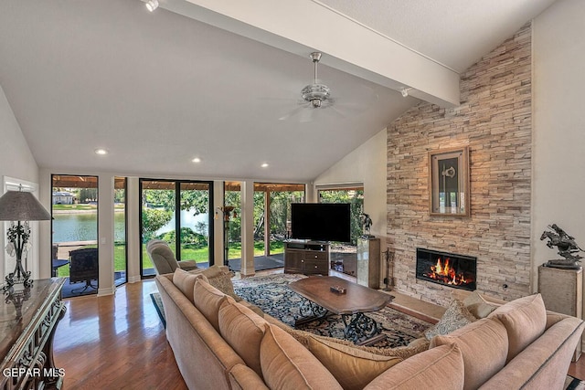 living room with hardwood / wood-style flooring, ceiling fan, a water view, a fireplace, and lofted ceiling with beams