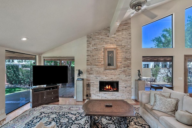 living room with a stone fireplace, high vaulted ceiling, beamed ceiling, ceiling fan, and a textured ceiling