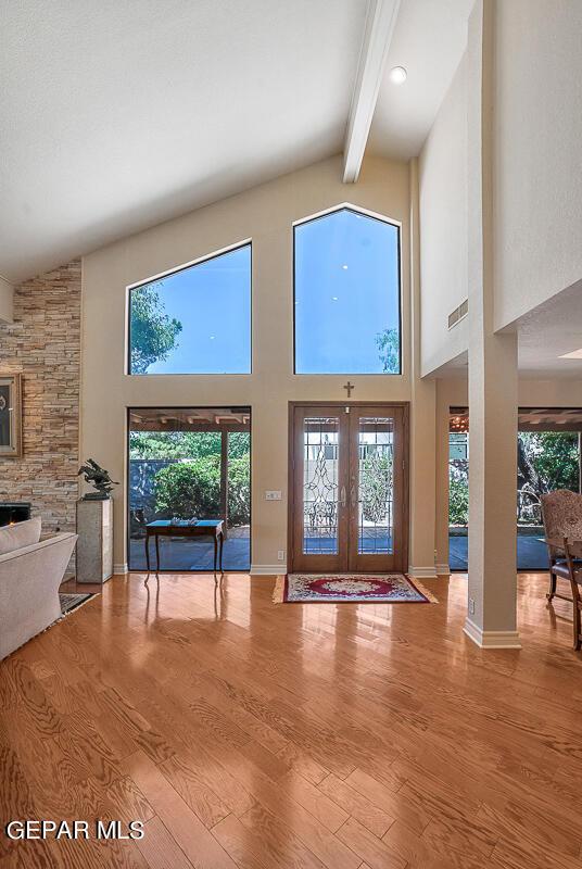 interior space featuring beamed ceiling, high vaulted ceiling, french doors, and hardwood / wood-style flooring