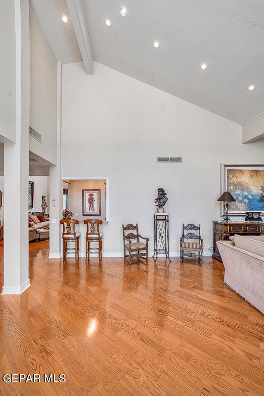 living area featuring beam ceiling, light hardwood / wood-style floors, and high vaulted ceiling