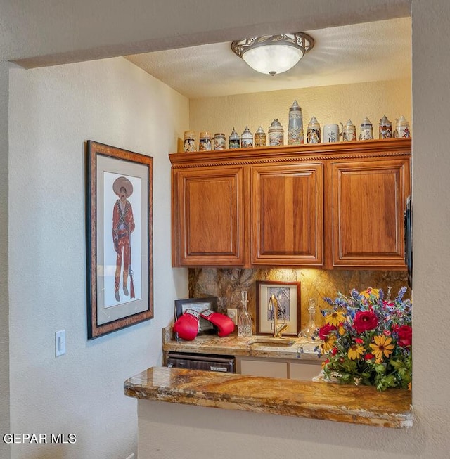 kitchen with backsplash, light stone countertops, and sink