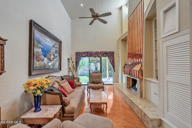 living room with a fireplace, a high ceiling, built in features, and light hardwood / wood-style flooring