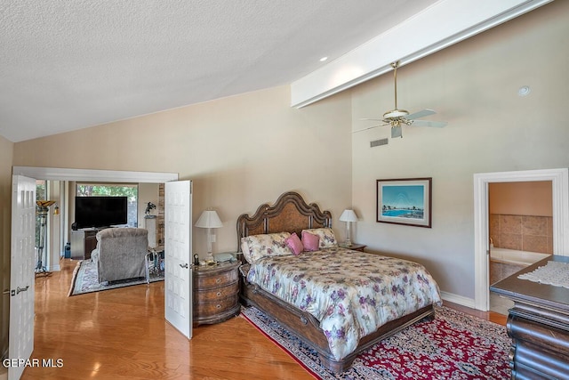 bedroom featuring hardwood / wood-style flooring, ceiling fan, ensuite bathroom, a textured ceiling, and vaulted ceiling