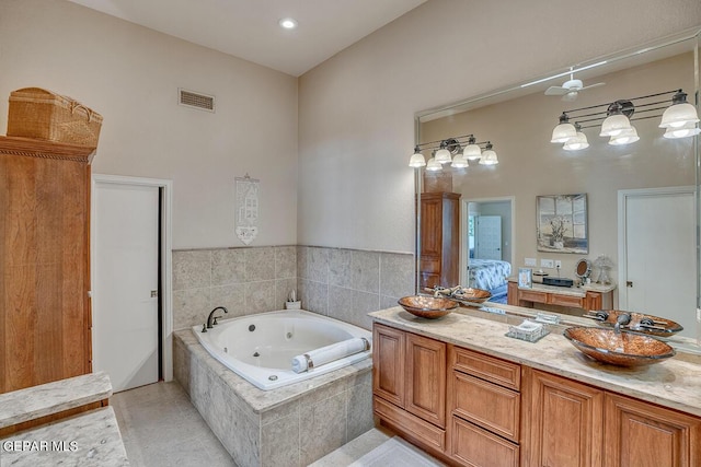 bathroom featuring tile patterned flooring, vanity, a relaxing tiled tub, and ceiling fan