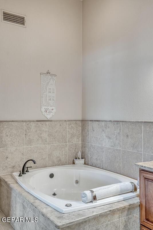 bathroom featuring vanity and tiled bath