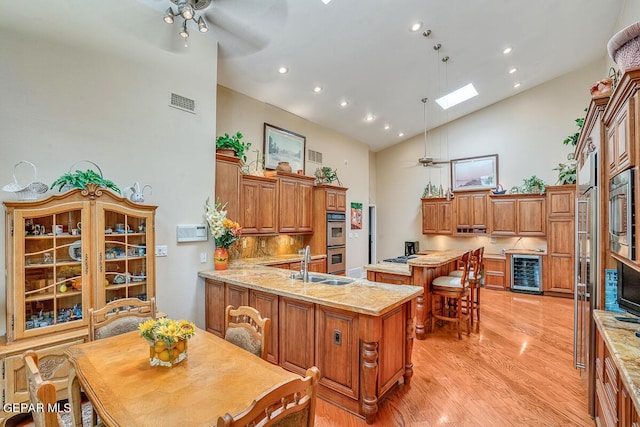 kitchen featuring high vaulted ceiling, a skylight, decorative light fixtures, wine cooler, and kitchen peninsula