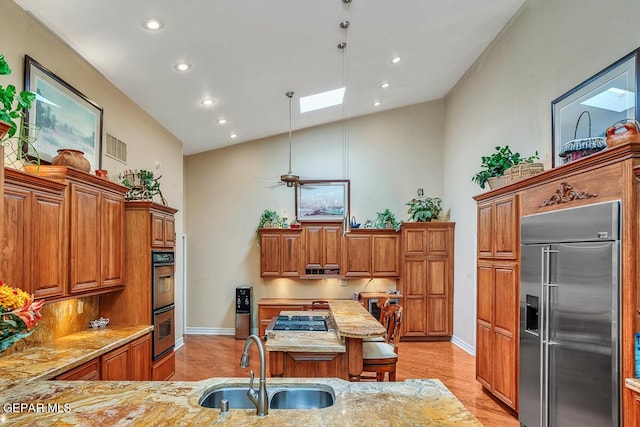 kitchen featuring sink, a skylight, high vaulted ceiling, pendant lighting, and stainless steel appliances