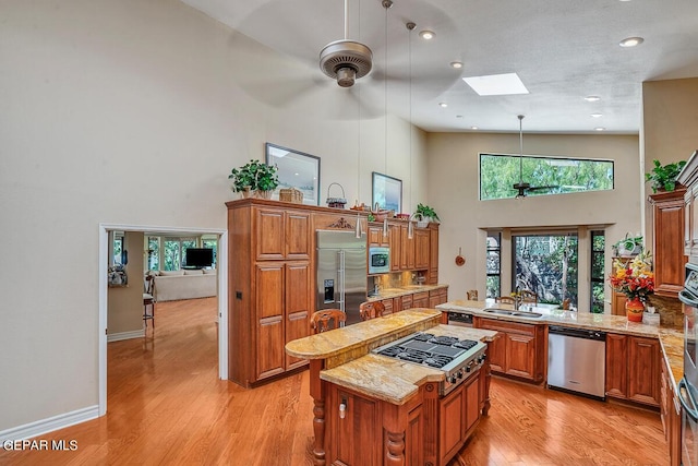 kitchen with built in appliances, hanging light fixtures, plenty of natural light, and a center island