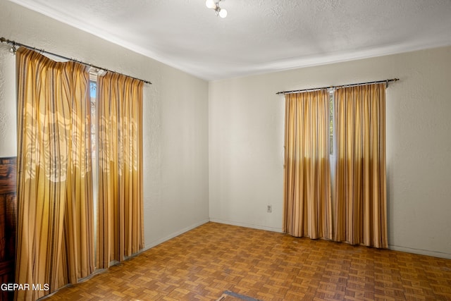 spare room featuring parquet flooring and a textured ceiling